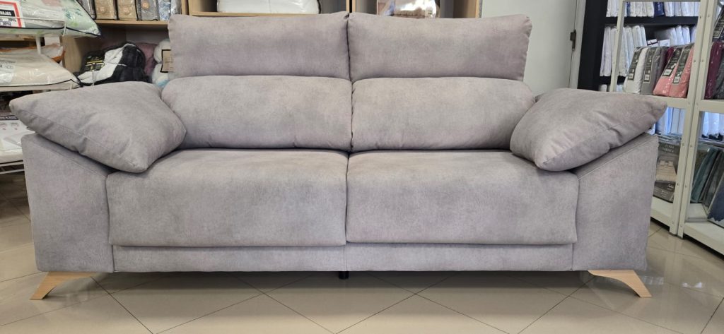 Sofá tapizado gris claro con cojín lateral, estructura moderna y mullida