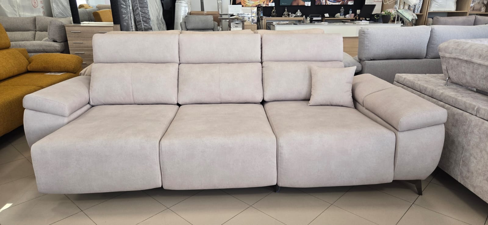 Sofá moderno con tapizado beige claro y líneas limpias, en exposición